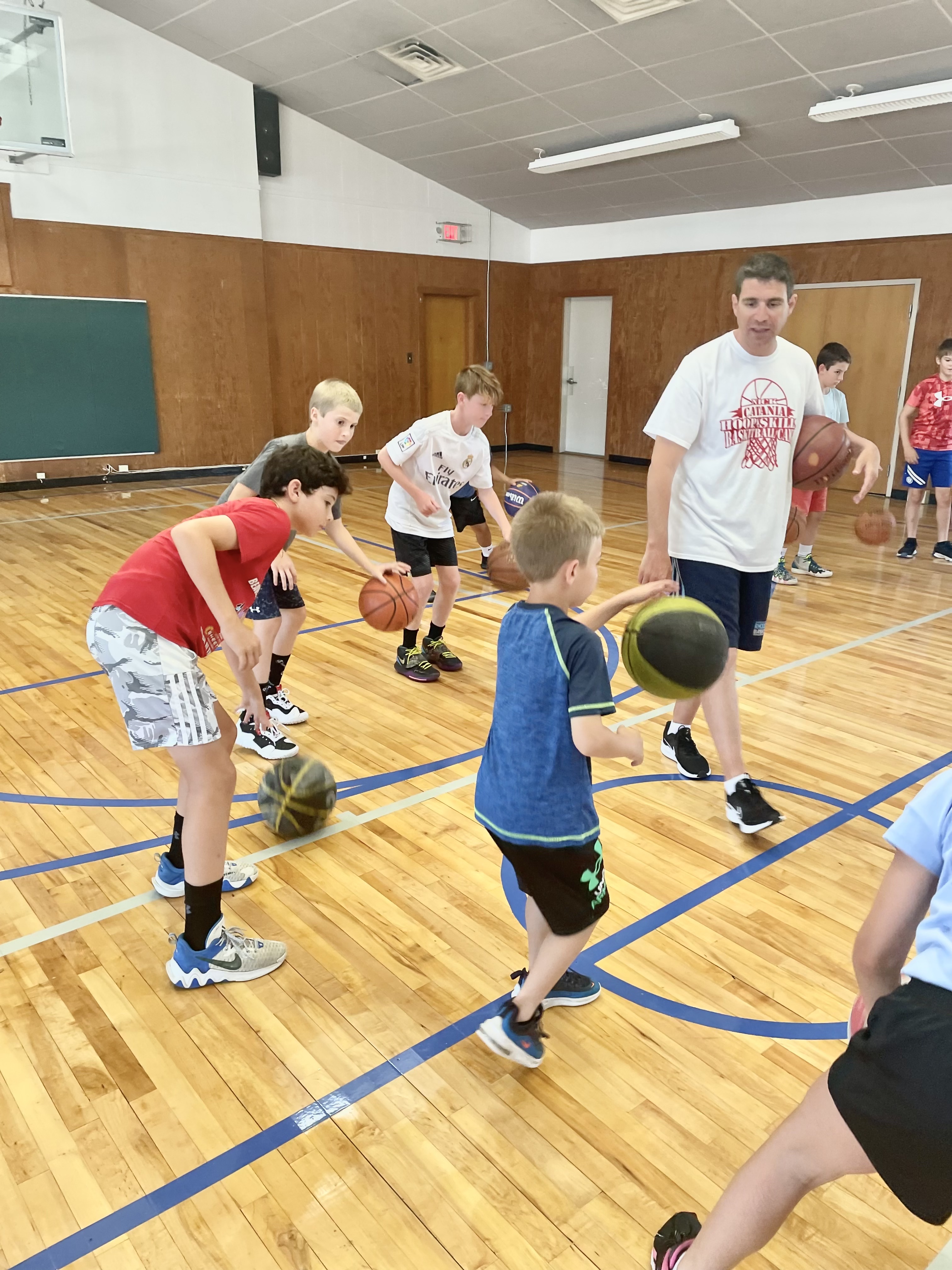 Coach Nick Catania leading a dribbling drill with campers at St. Denis Gym